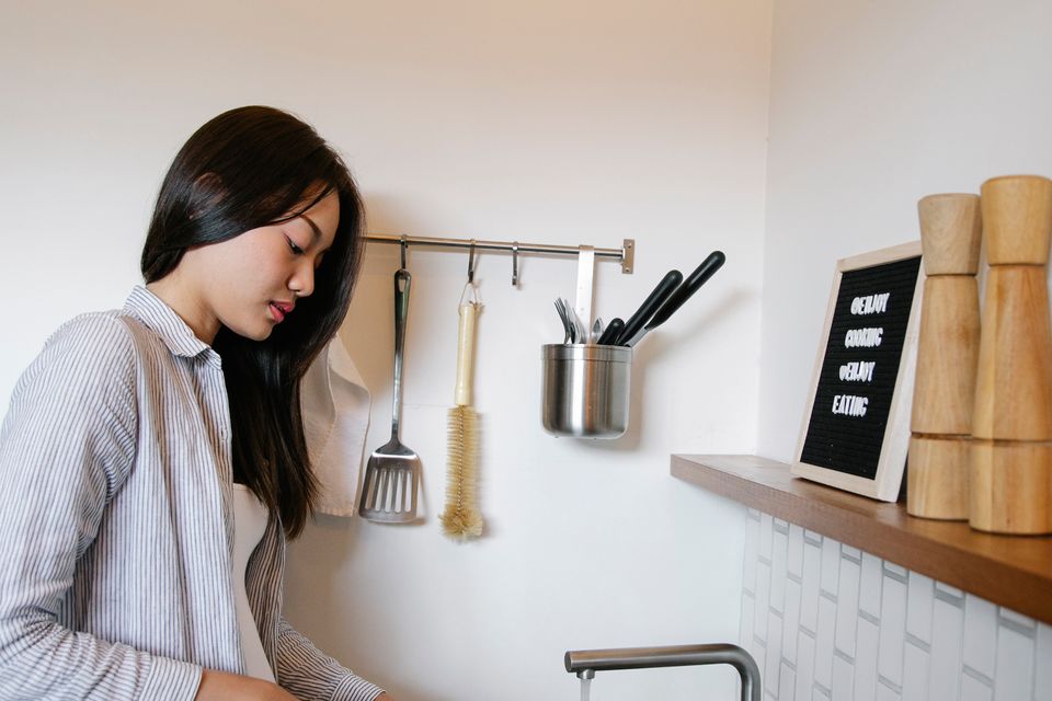 Người phụ nữ châu Á làm sạch khu vực bếp dưới ánh sáng tự nhiên