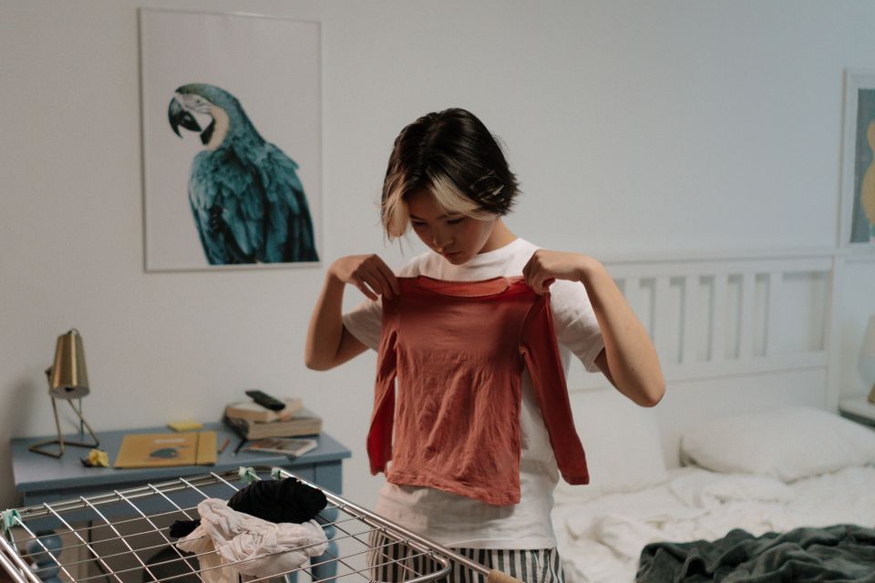 Người phụ nữ châu Á gấp quần áo trong phòng ngủ