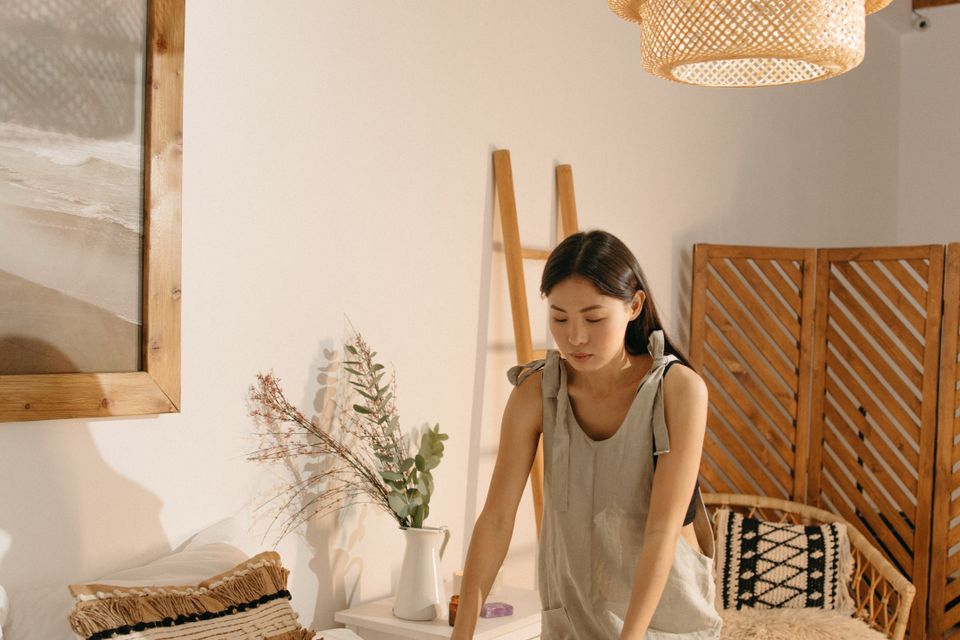 Người phụ nữ châu Á gấp vải trong phòng ngủ tối giản